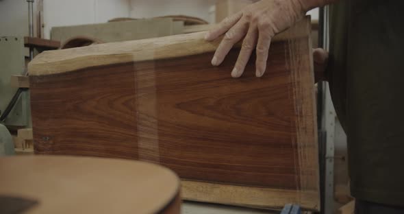 Luthier lifts a wooden block places it back