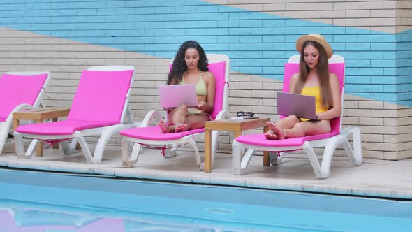 Two Millennial Girls Relax in Sun Loungers By Summer Pool alt