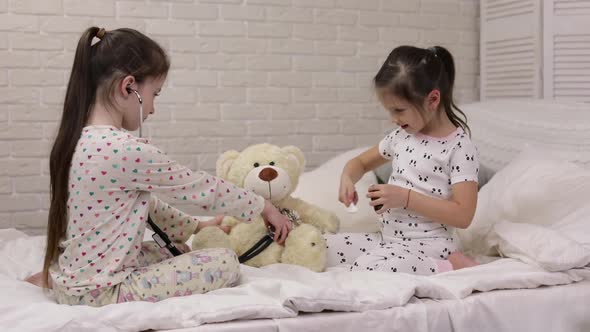 Two Cute Children Girls Playing Doctor with Teddy Bear