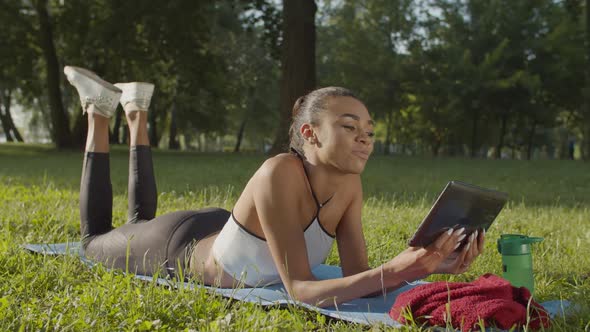 Woman with Tablet Pc Relaxing After Workout in Park alt