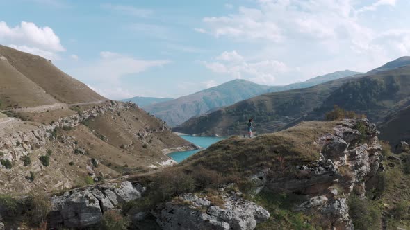 Woman runs up hill near Bylym lake  with azure water among old mountains alt