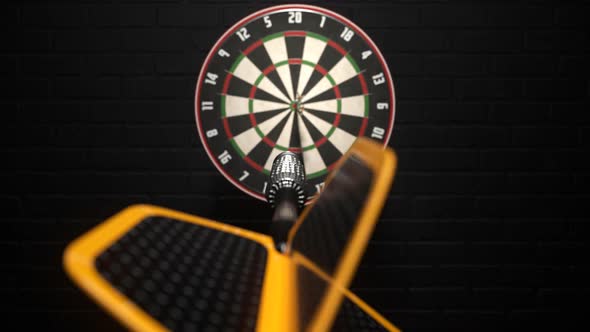 Darts arrow hitting in the bullseye of the dartboard hanging on the dark wall. alt