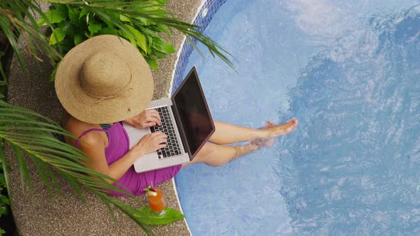 Woman sitting on edge of hot tub using laptop computer. Shot on RED EPIC for high quality 4K, UHD, U alt