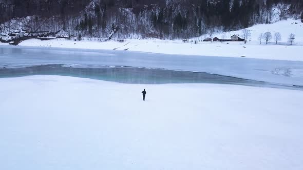 The drone follows a young photographer who is walking through the snow in the Klöntal, Switzerland. alt