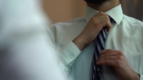 Man tying a tie. Businessman getting dressed. alt