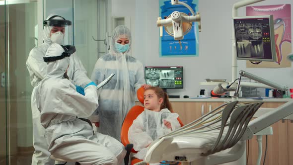 Pediatric Dentist and Nurse in Ppe Suit Interrogating Kid Patient alt