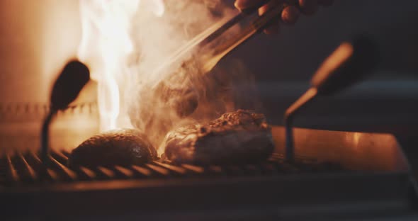 Close up of professional chef using fire grill to cook meat alt