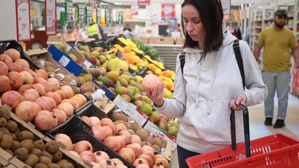 Midrange Caucasian Woman in a White Sweater in a Shopping Mall with Fruits in a Supermarket Buys a alt