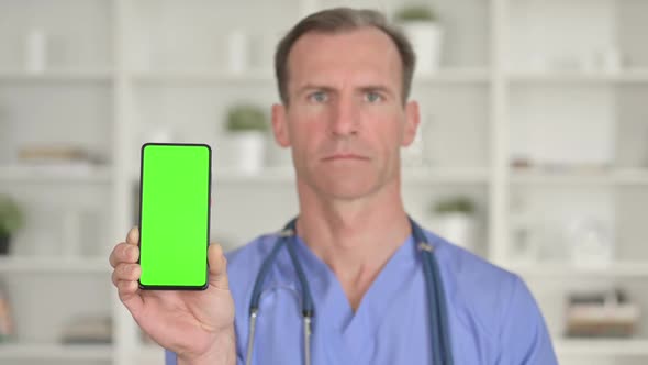 Portrait of Middle Age Doctor Holding Smartphone with Chroma Screen alt