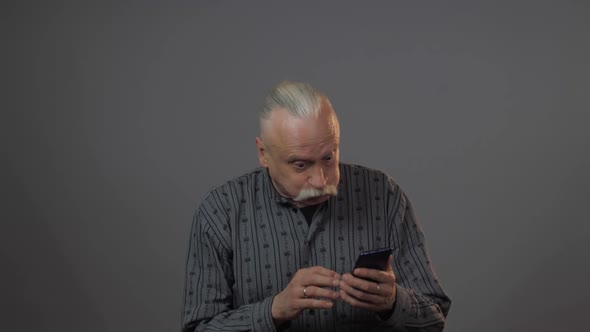 Aged Man Holds Gadget Looks at Telephone Upsets and Cries alt