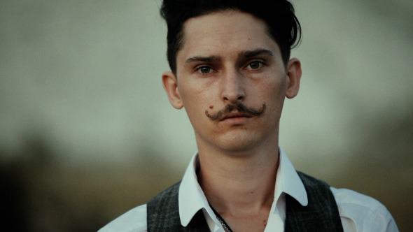 A Young Man With A Mustache Looking At You alt