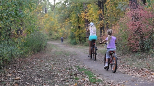 Mother And Daughter On a Bicycle In Autumn Forest