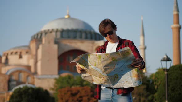 Man Tourist Looking at Map Against Ayasofya Mosque Travel Concept alt