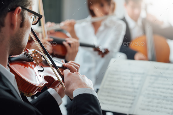 Violinist performing with classical orchestra - Stock Photo - Images