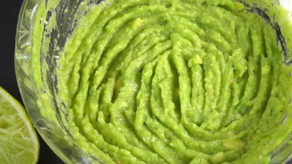 Guacamole dip rotating in glass bowl background. Cooking healthy food. Making avocado dip alt
