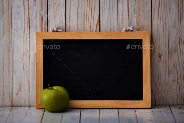 Chalkboard and green apple on wooden background