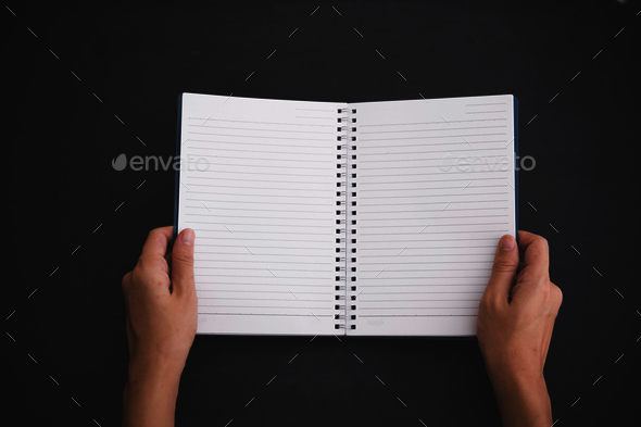 Hand open a notebook, black background. Mock up