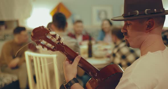Young Male Guitar Player with a Hat Playing for His Friends alt