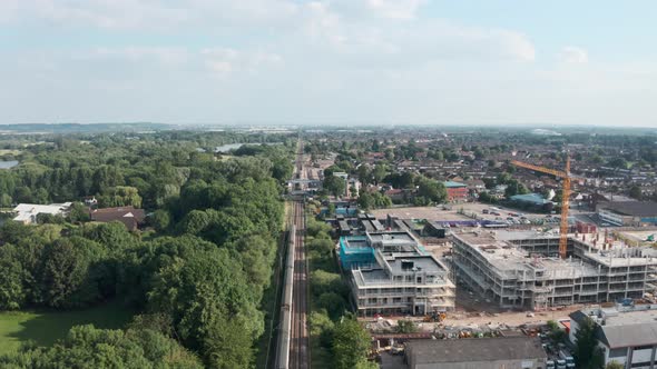 Low follow drone shot over British rail train entering Cheshunt station north London alt