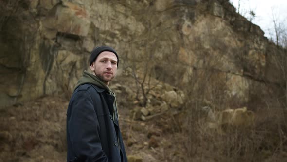 Stylish Young Guy Standing In Nature. Behind Him Is Rock. alt