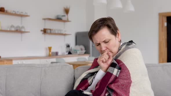 Senior Woman Coughs While Sitting on the Couch alt