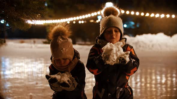 Two Little Kids Standing on Ice Rink and Throwing Snow in the Air alt