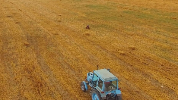 Rural Tractor Making Hay Bales In Stubble Field