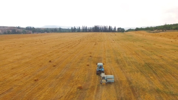 Tractor Baler Making Straw Bales In Stubble Field