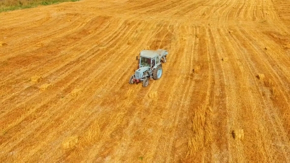 Tractor Baler Moving Across Yellow Stubble Field