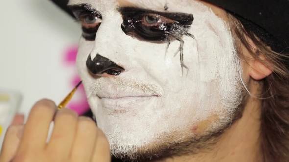 Artist Hand Painting Man's Nose Black At Halloween