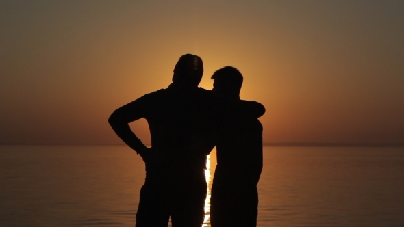 Happy Gay Couple  Watching Sunset On The Beach