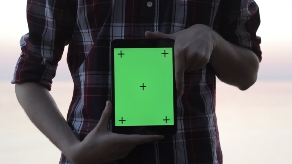 Man Holding a Tablet With a Green Screen