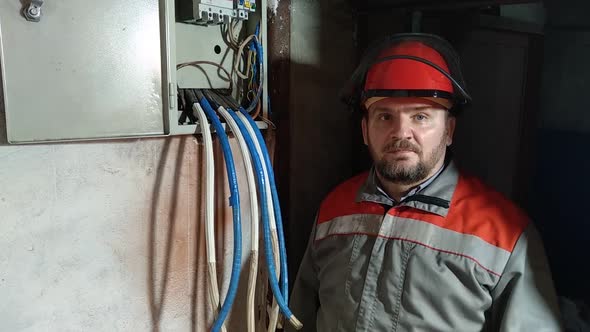 Electrician in a helmet. He covers his face with a protective mask.