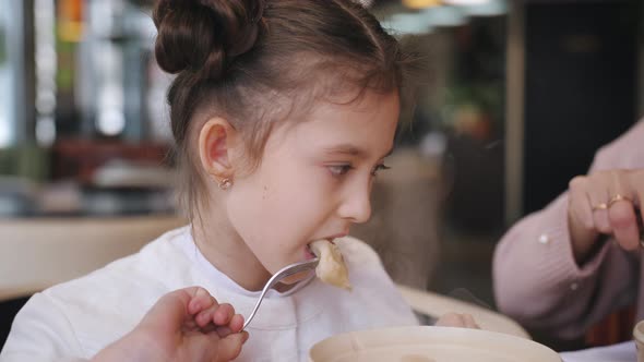 Little Girl Eating Hot Dumplings in the Cafe