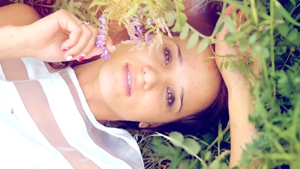 Young Cute Summer Brunette Girl Lying On a Flower