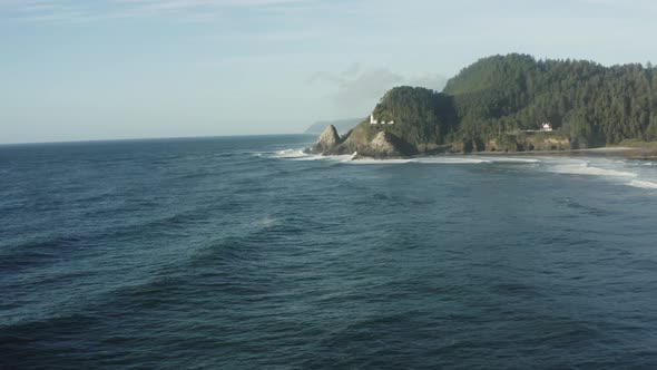 Forward tracking aerial over deep blue ocean toward Haceta Head lighthouse alt