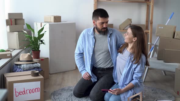 Young Family Moved to a New House Moving Concept Couple Sitting on the Floor Rejoicing in New alt