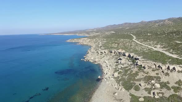 Slow aerial push in across land and beautiful clear turquoise sea on the coast of Akamas Peninsula i alt