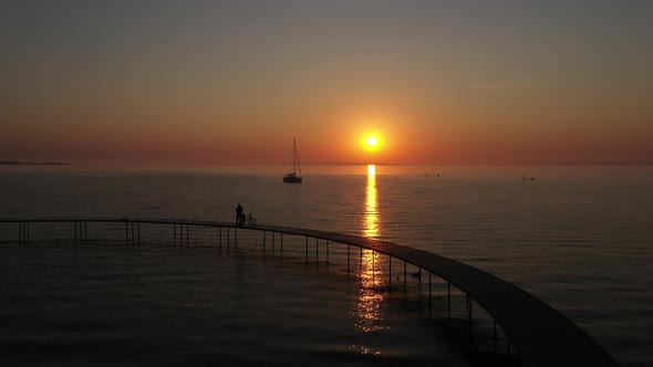 Silhouette of Man and Bicycle on Infinite Bridge in Denmark and Majestic Sunset alt