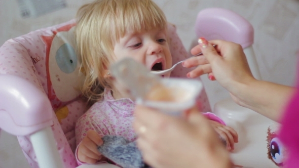 Small Child Eats Food From a Spoon