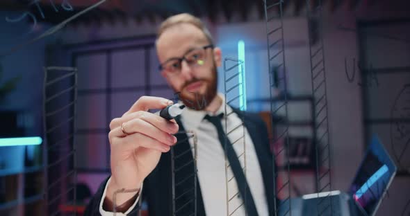 Man in Formal Wear in Glasses Standing Near Glass Board and Writing Important Notes on this Board alt