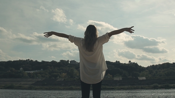 Girl Stands Near The River And Joyfully Lifts