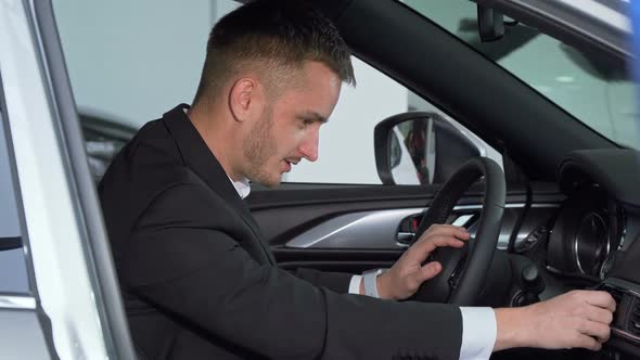 Businessman Sitting in a New Car, Checking Out Interior of a Vehicle alt