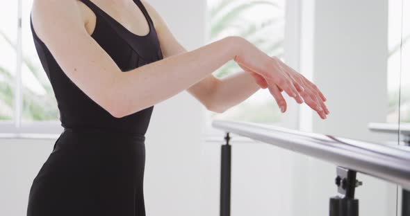 Caucasian female ballet dancer practicing up by the mirror for dance class in a bright studio alt