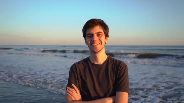 Happy Young Man Standing On Beach With Crossed Arms. - zoom out, slow motion alt