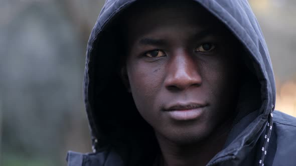 Thoughtful confident hooded young black african looking at camera in the street alt