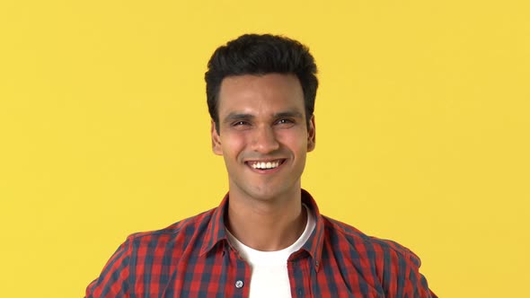 Young handsome Indian man in casual red tartan shirt smiling and looking up