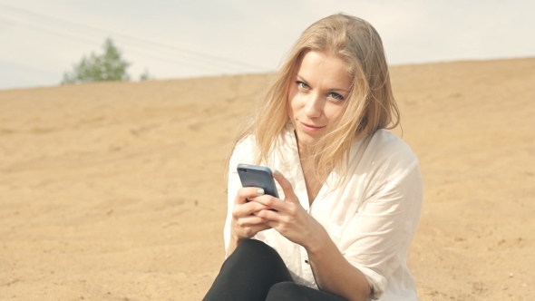 Girl Sitting In The Sand Against The Backdrop Of