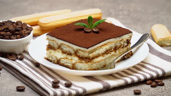 Portion of Traditional Italian Tiramisu dessert on grey concrete background alt