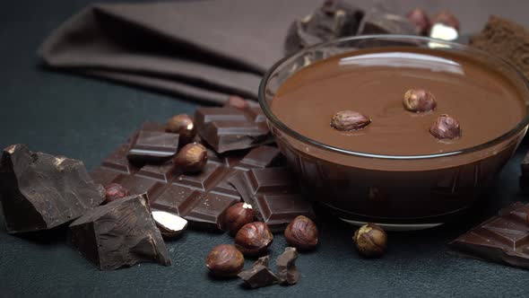 Glass Bowl of Chocolate Cream or Melted Chocolate, Pieces of Chocolate and Hazelnuts alt